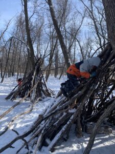 Kids climbing on stick shelters in Bois Des Esprits, winter 2021. Photo by Mira Oberman
